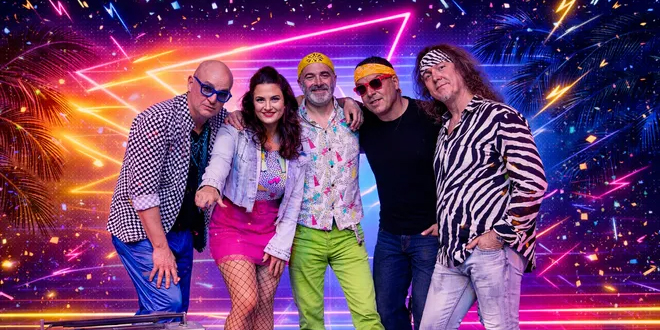 Five band members pose together against a colorful neon backdrop with palm trees and fireworks. They wear bright, retro-style clothing, including patterned shirts, sunglasses, bandanas, pink pants, and green pants.